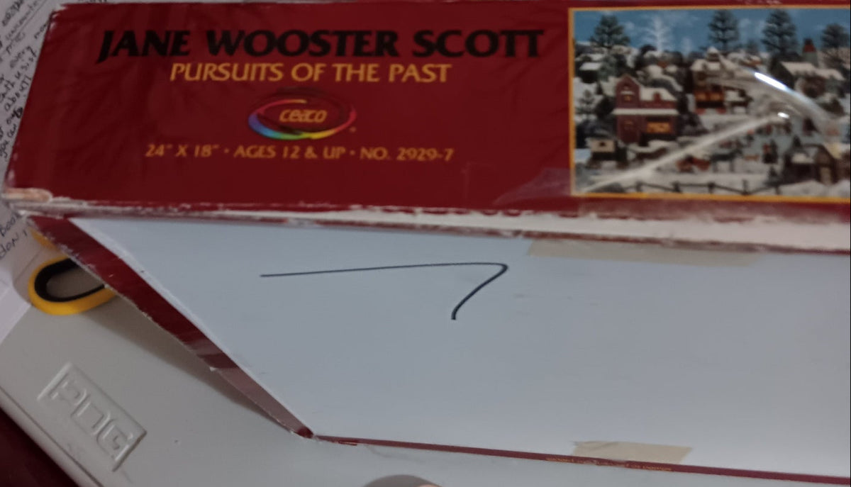 A side of the box for the puzzle Pursuits of the Past by Jane Wooster Scott. Manufactured by Ceaco.