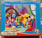A Disney Clubhouse Mickey Mouse 12-piece jigsaw puzzle box, placed on a green puzzle mat with loose puzzle pieces scattered around.