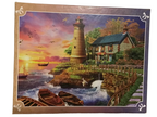 A completed jigsaw puzzle featuring a scenic lighthouse by the sea at sunset, displayed flat on a wooden surface against a white textured wall.