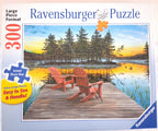 Ravensburger 300-piece jigsaw puzzle box featuring a scenic lake sunset with two red Adirondack chairs on a wooden dock, trees, and ducks. The box includes product text and graphics on a white background.