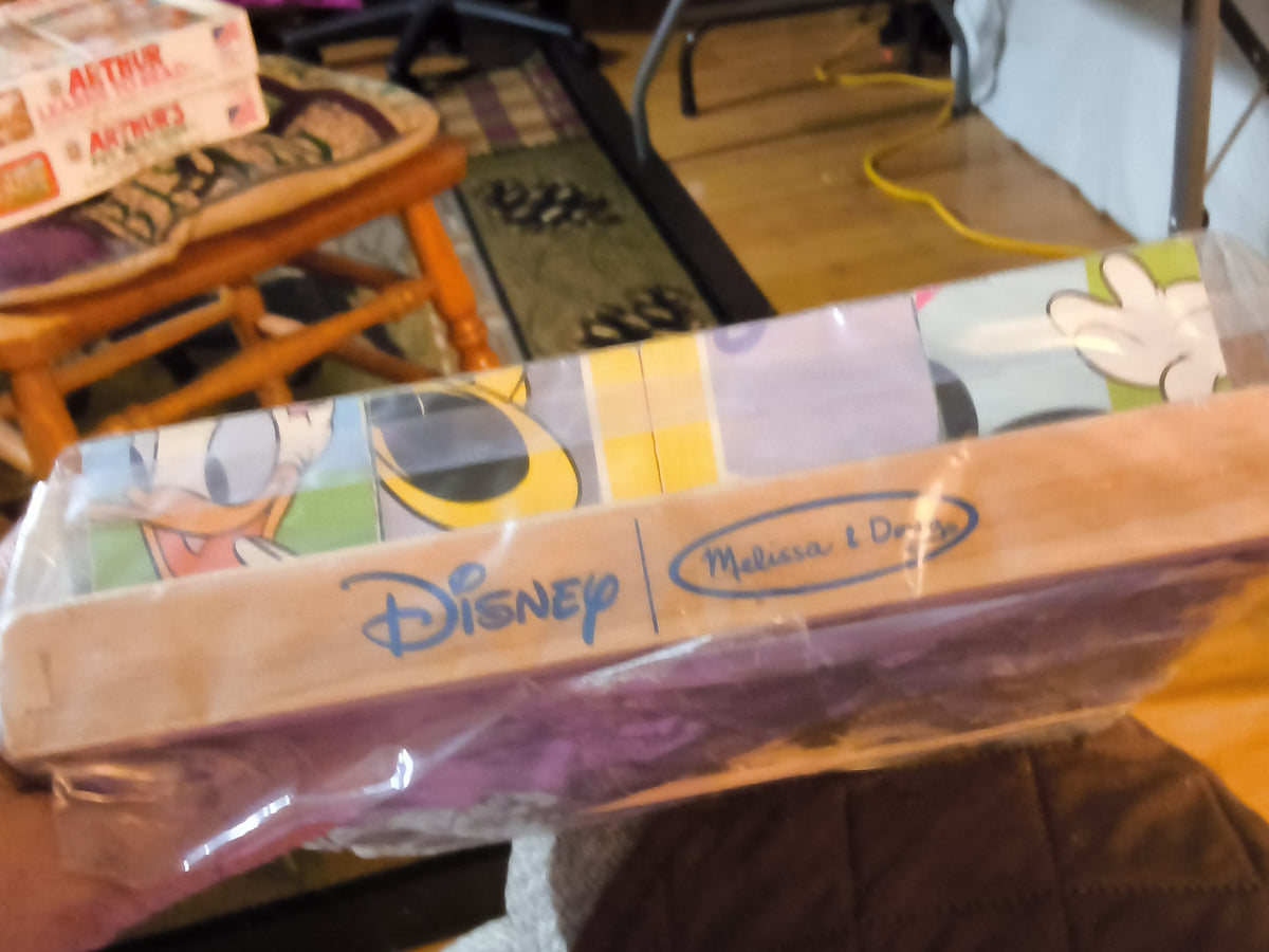A packaged Melissa & Doug Disney wooden toy set in clear plastic wrapping. 