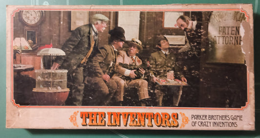 Vintage toy game box for 'The Inventors' by Parker Brothers, featuring a colorful illustration of men inventing on a green cutting mat background.