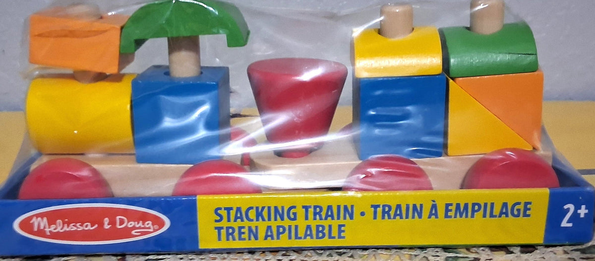 Melissa & Doug stacking train toy in its original retail packaging, featuring colorful wooden blocks and shapes on a train-shaped base.
